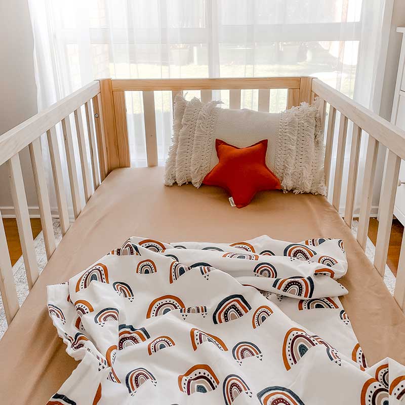 Snuggly Jacks Camel Fitted Cot Sheet on a wooden cot baby cot with a Rainbow Dusk Minky Blanket