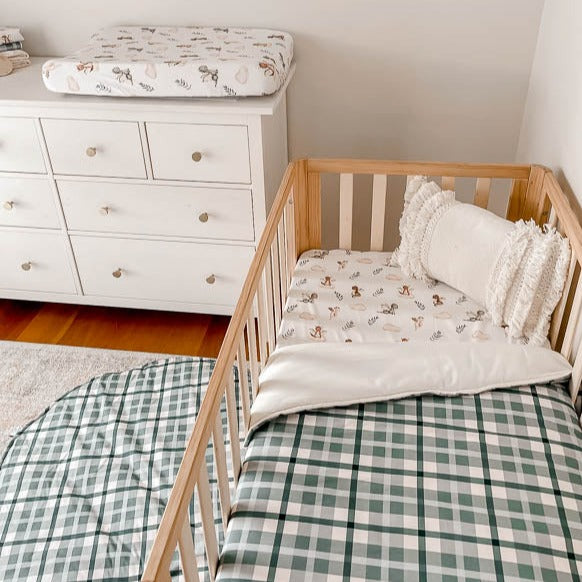 Modern nursery set up with blue plaid playmat, blue plaid quilt and a dragon print change mat cover on a white chest of draws