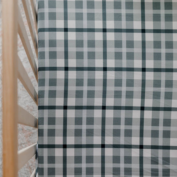 a close shot of a pine cot set with a blue plaid fitted cot sheet