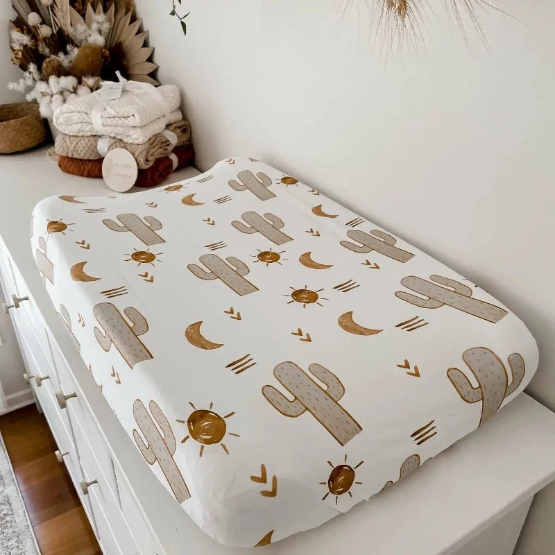 Change table with a mat covered in a sage, white, cactus printed snuggly jacks cotton sheet