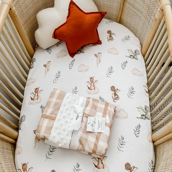Earthy plaid dimple dot minky presented on top of a white bassinet sheet in a rattan bassinet