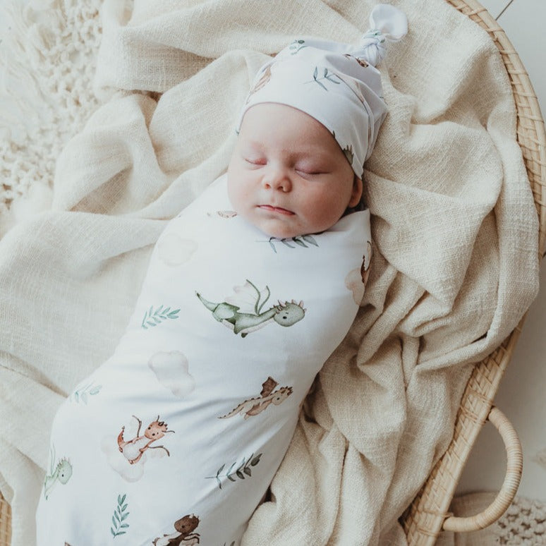 Adorable baby laying on top of a cotton wrap set inside a rattan bassinet