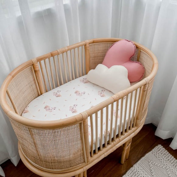 Soft white cotton bassinet sheet with swans in a rattan bassinet.