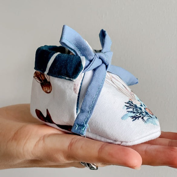 a Pair of baby booties made from Snuggly Jacks Ocean Jersey Fabric on a womens hand.