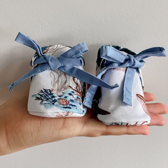 a Pair of baby booties made from Snuggly Jacks Ocean Jersey Fabric on a womens hand