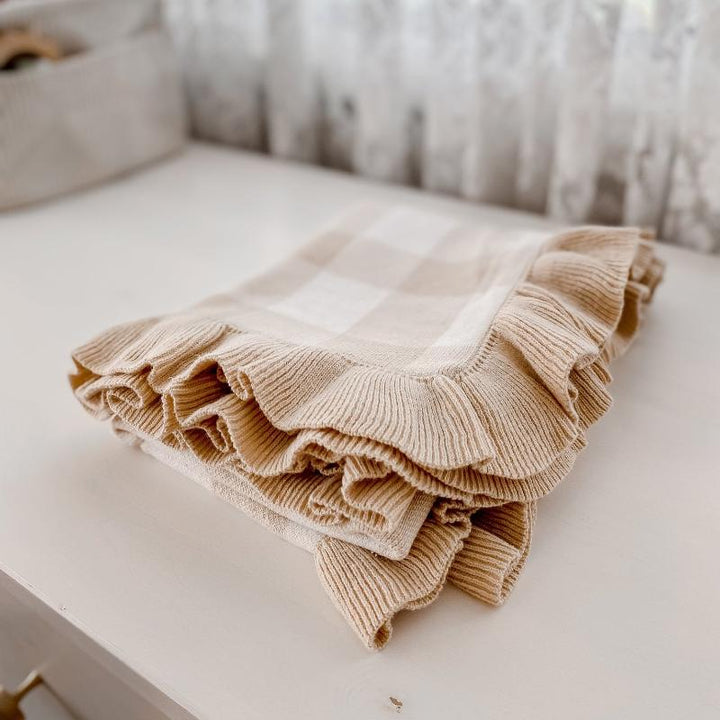 Knitted sand gingham baby blanket with frill detail, crafted from soft organic cotton for cozy nursery styling.