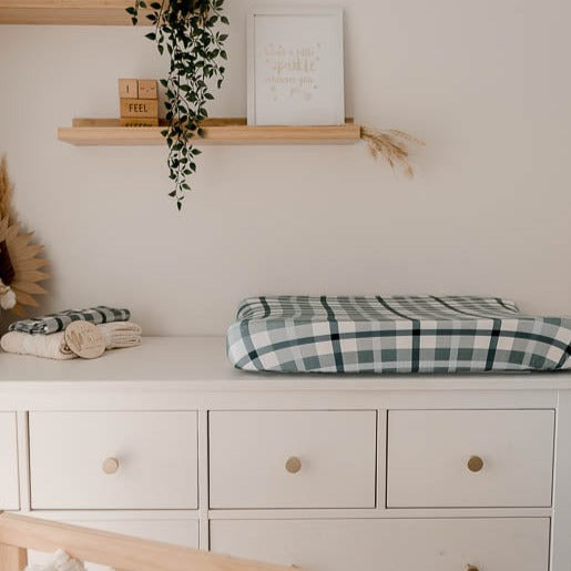 Square side shot of a white chest of draws with a change mat and a pile of burp cloths presented to show the beautiful blue plaid design.