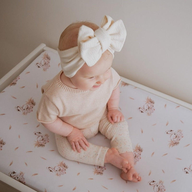 Sweet baby sitting on a change table wearing a cute linen bow.