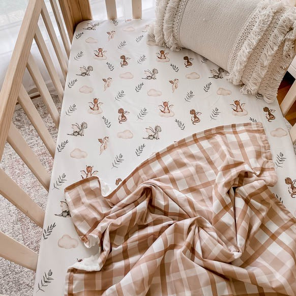 Pine cot made up with a cotton fitted cot sheet with a brown plaid dimple dot minky blanket laid across it