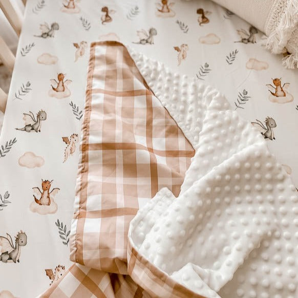 Close image of a minky pram blanket laid over a 100% cotton sheet with dragon prints