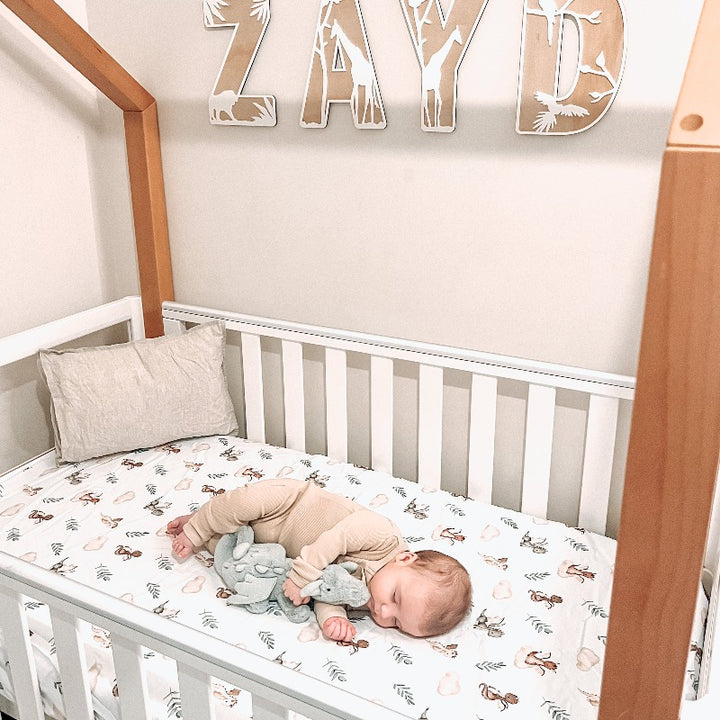 A cute a frame cot, fitted cot sheet from snuggly jacks demonstrating a dragon print with alternating leaves and clouds.