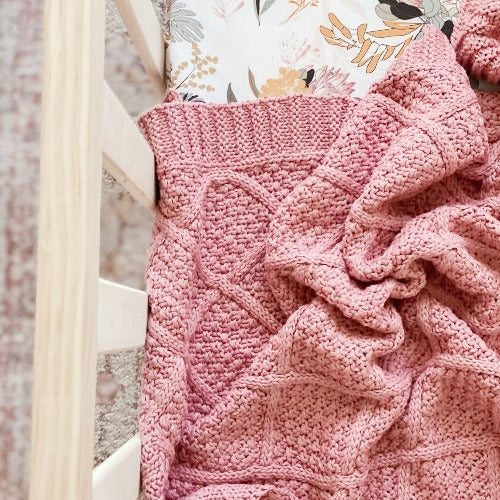 Rose pink cotton knitted blanket from Snuggly Jacks, suitable for baby or nursery, shown with a lovely baby