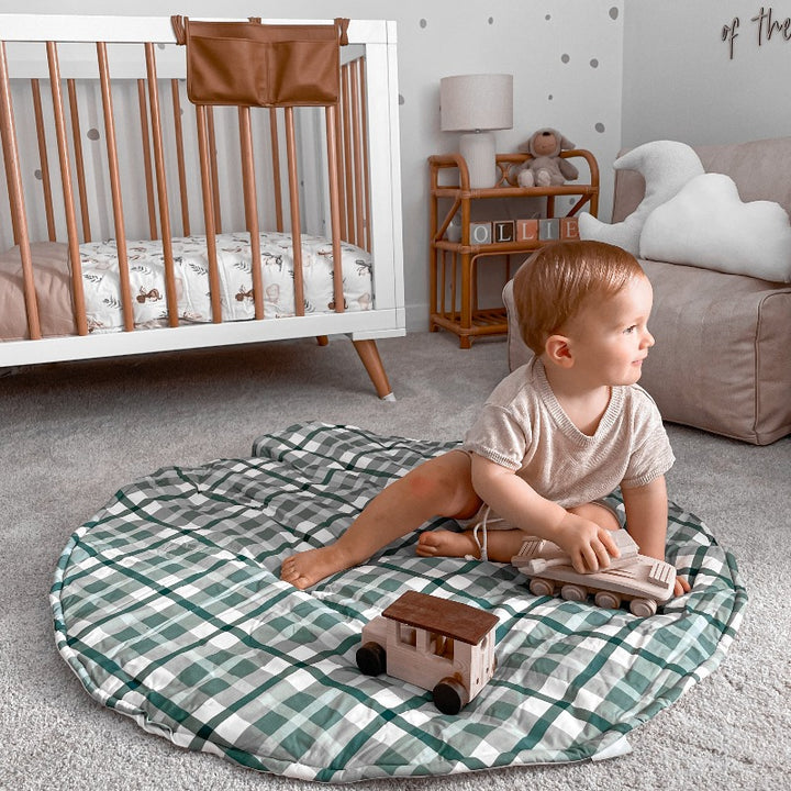 Toddler using his wooden toys on a blue plaid playmat in a modern nursery