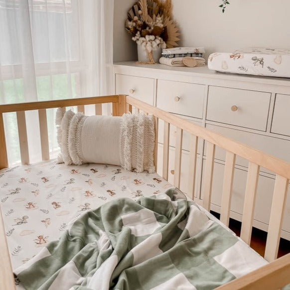 Modern nursery designed using dragon prints on a fitted cot sheet, bassinet cover and burp cloths.