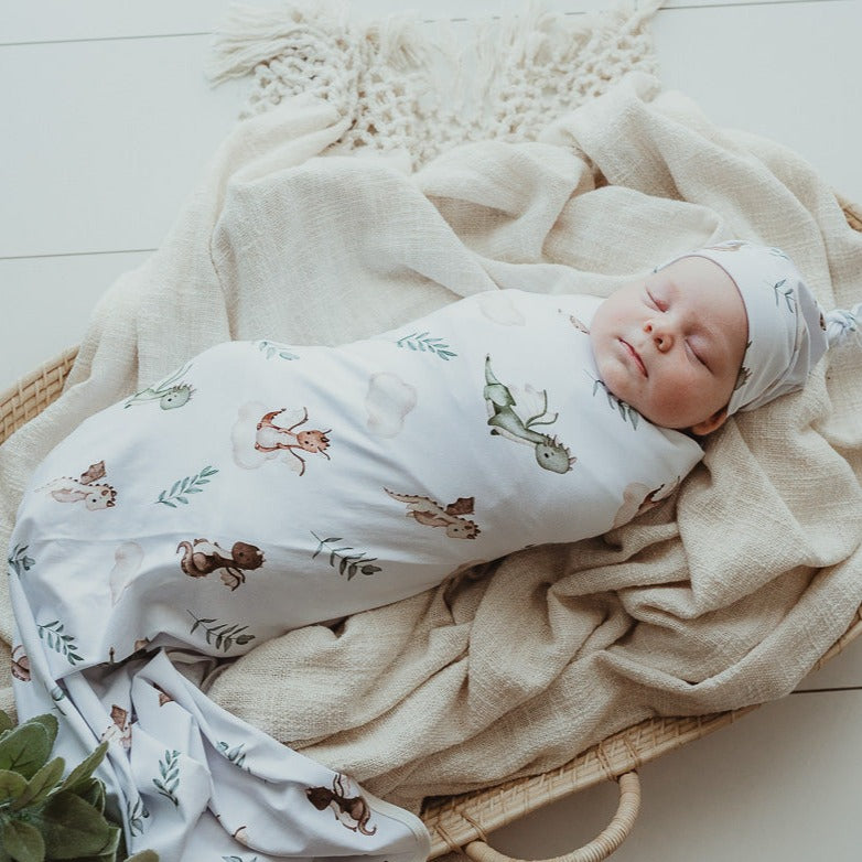 Tightly swaddled baby laying in a rattan moses basket and dreaming about all the sweet things