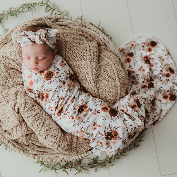 Sweet little baby snuggled in to a taupe knitted blanket and wrapped in a warm floral jersey stretch wrap 