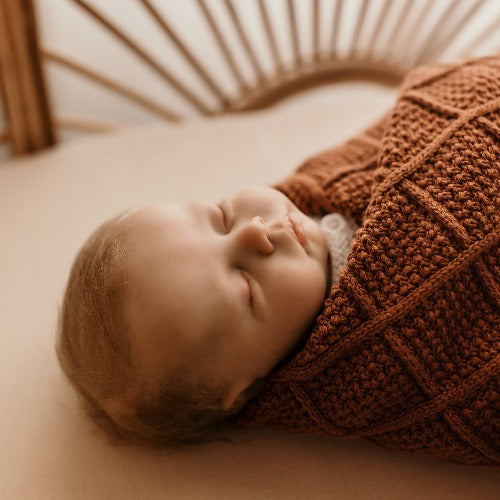 newborn baby wrapped in a snuggly jacks organic knitted blanket in cinnamon