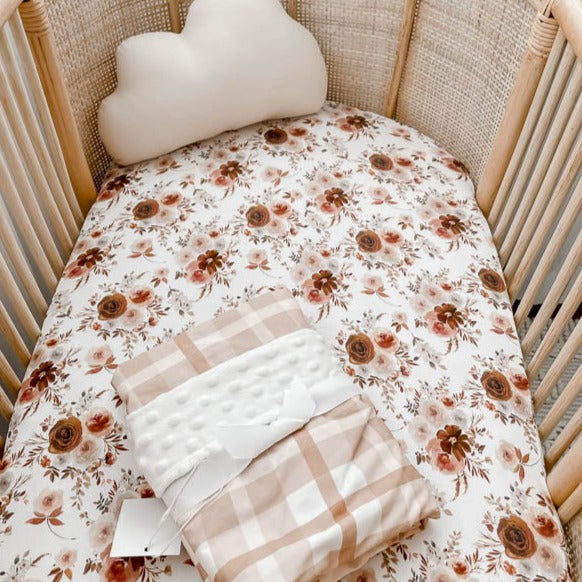 Rattan bassinet with a floral bassinet sheet made from cotton, presented with a snuggly jacks dimple dot minky blanket placed on top.