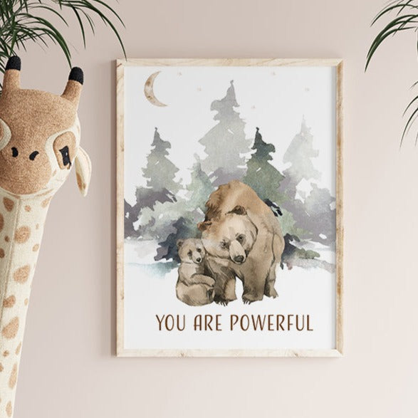 Picture of a brown bear and her cub walking in the forest, in a brown frame hanging on a nursery room wall next