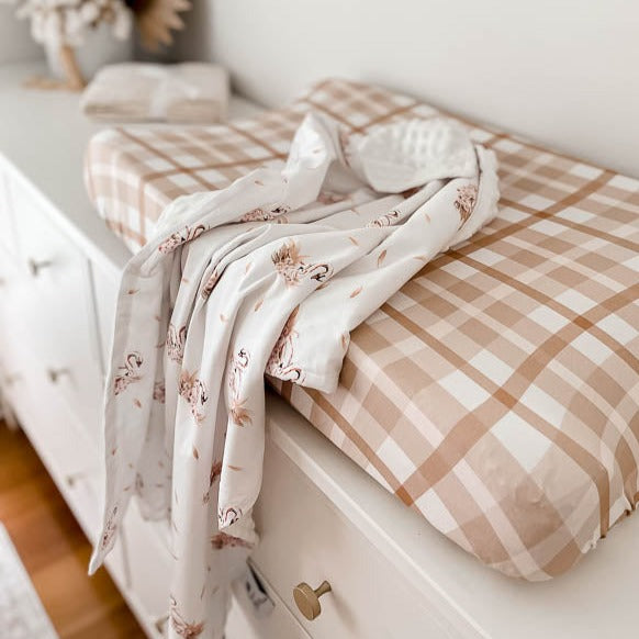 Swan printed dimple dot minky draped over a change mat with a cotton cover sitting on a white chest of draws.